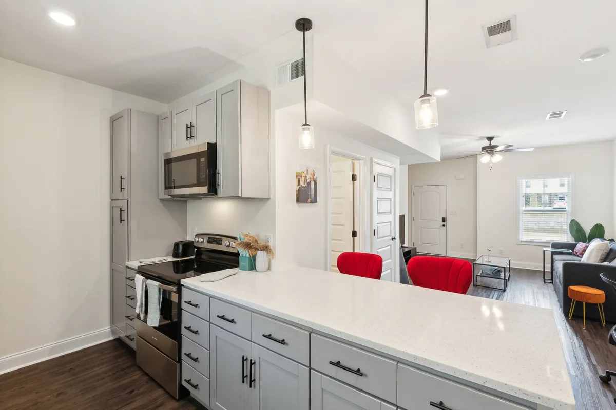 This image captures a bright and spacious open-concept area, seamlessly integrating a kitchen island, modern appliances, comfortable dining area seating, and a view of the living room area. The space is filled with natural light, enhanced by stylish contemporary furnishings, making it ideal for gatherings and relaxation.