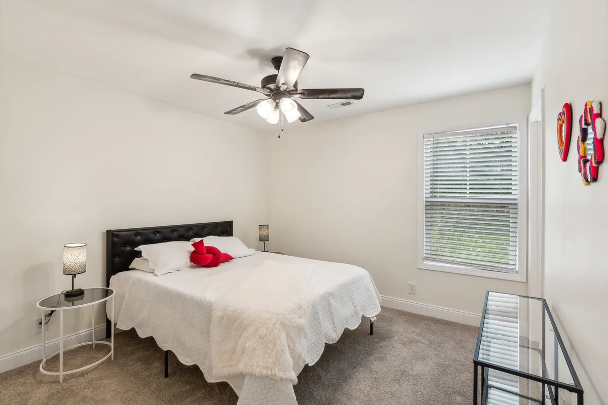A tranquil bedroom scene with a soft, inviting bed, a modern lamp casting gentle light, decorative heart accents, and a bright window letting in natural sunlight. The room exudes warmth and relaxation, ideal for unwinding after a busy day.