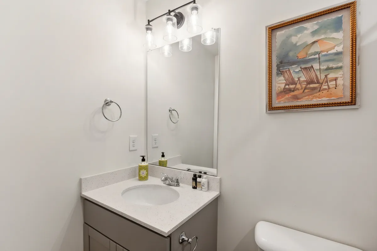 A well-appointed bathroom vanity with a large mirror, elegant lighting, and tasteful art. The setup invites self-care routines in a serene, thoughtfully designed space.